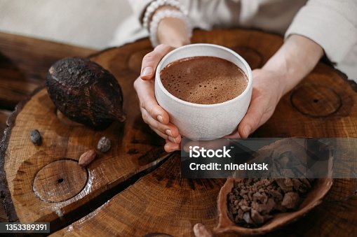 istock Person giving ceremonial cacao in cup. chocolate drink top view 1353389391