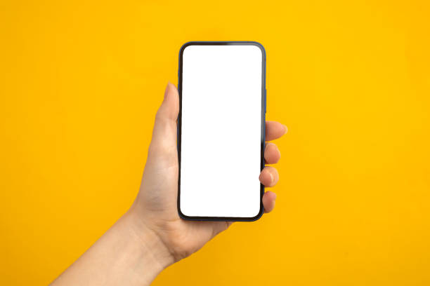 Person holding mobile phone with blank white screen on a yellow background, copy space photo Person holding mobile phone with blank white screen on a yellow background, copy space vlad model photos stock pictures, royalty-free photos & images
