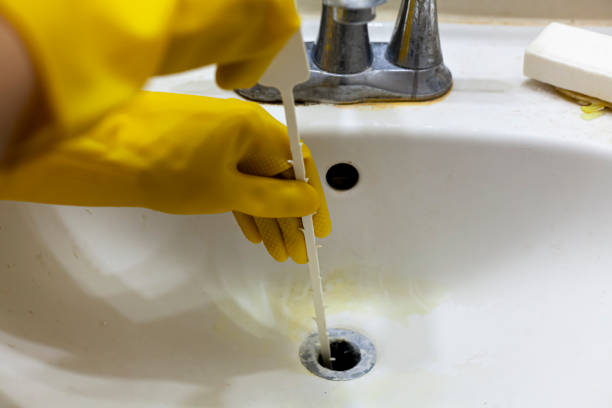 A person is trying to unclog the drain of a sink using plastic disposable snake auger tool stock photo