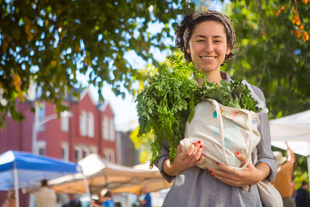 Person leaving farmers market with large bag of vegetables stock photo