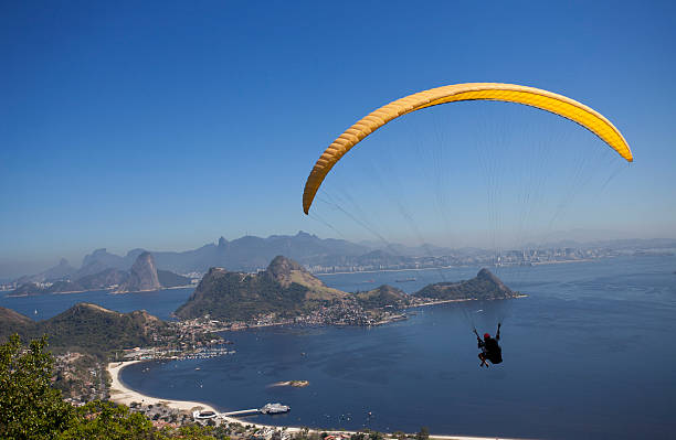 A person paragliding over calm blue sea in Rio de Janeiro  stock photo