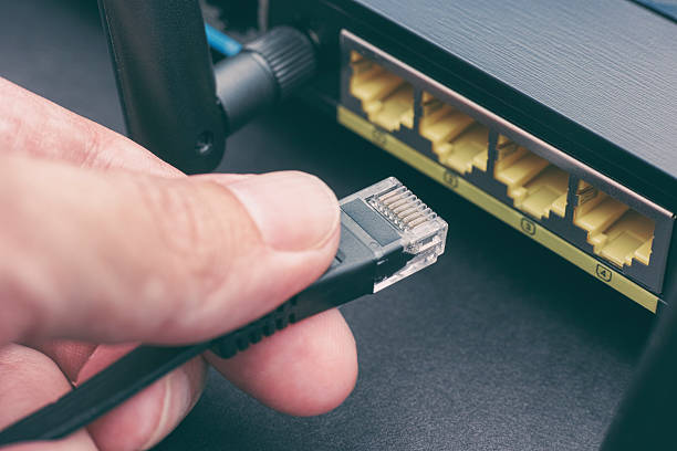 persona que conecta el cable al router inalámbrico - cable de ordenador fotografías e imágenes de stock