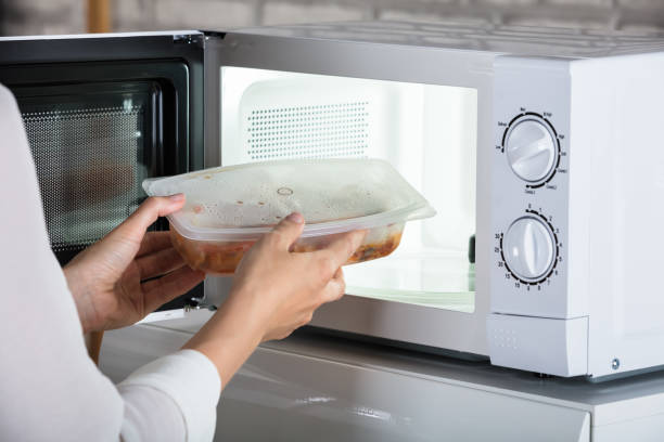 Person Removing Prepared Food Close-up Of A Person Removing Prepared Food From Microwave Oven microwave stock pictures, royalty-free photos & images