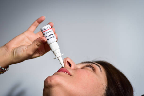 Person taking COVID-19 coronavirus nasal spray vaccine stock photo