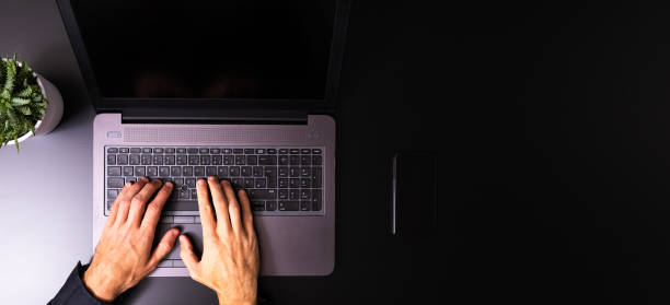 Person using a laptop computer on a solid color background stock photo
