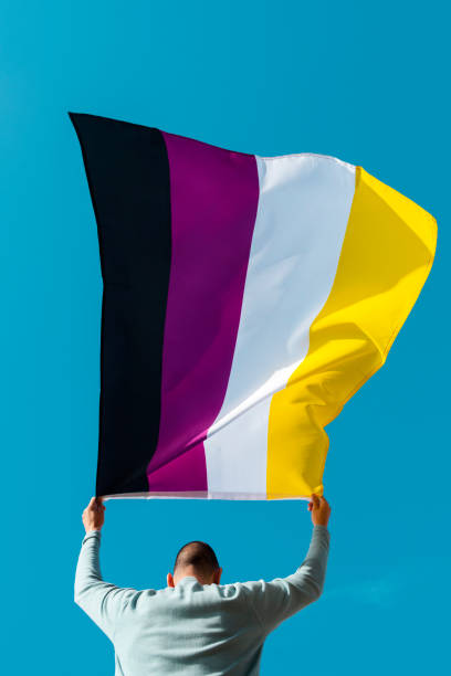 person waving a non-binary pride flag stock photo