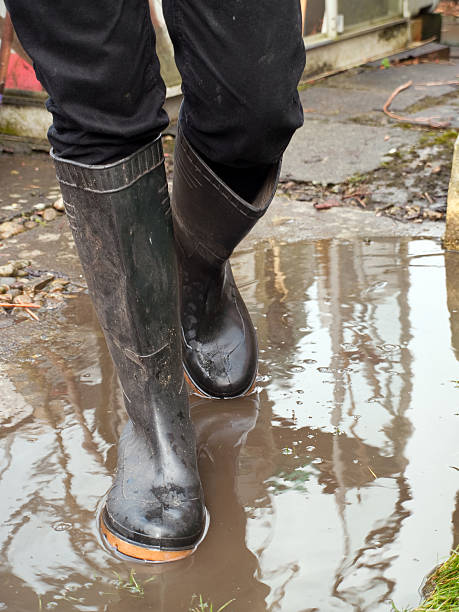 Person wearing wellington boots stood in muddy water stock photo