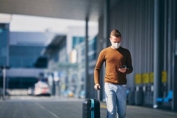 Personal protection during traveling Man wearing face mask and walking to airport terminal. Themes traveling during pandemic and personal protection. passenger stock pictures, royalty-free photos & images