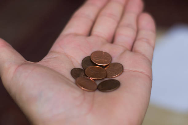 Persons hand holding out a a handful of United States of America (USA) pennies, a useless coin on a brown background. Money exchange. Selective Focus stock photo