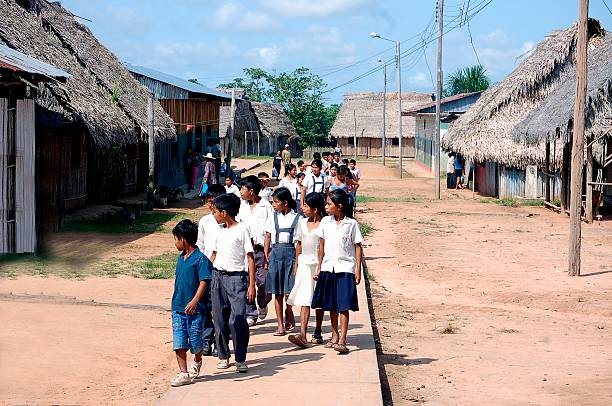 Peruvian Children Walking To School Huacaraico, Peru - August 17, 2005: A group of Peruvian school children in uniforms in the Peruvian Amazon village of Huacaraico walking home from school. They\'re looking off to the side at a rooster while walking on the cement walkway through the middle of the village. peru girl stock pictures, royalty-free photos & images