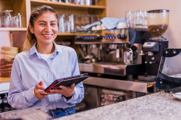 Peruvian entrepreneur doing inventory with touchscreen. Young Latinx businesswoman south America Peru cafe bar owner. female waitress using technology from a tablet and internet. peru woman stock pictures, royalty-free photos & images