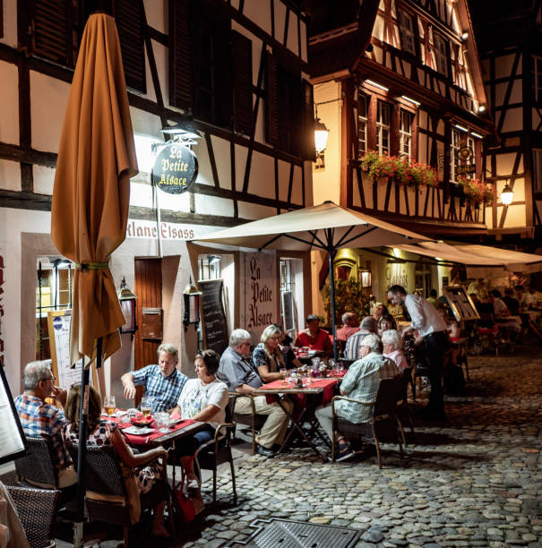 Petite France Strasbourg France Strasbourg France , August 08th of 2018 People sitting in outside terraces in Petit France quarter in Strasbourg France. This historic part of the city is considered a Unesco Heritage site with old half timbered houses from the XVO and XVII century and surrounded by canals. Nowadays it is a very visited travel destination. petite france strasbourg stock pictures, royalty-free photos & images