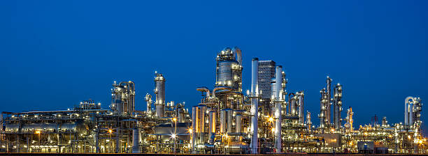 Petrochemical Plant At Dusk A panoramic view of a modern, illuminated petrochemical plant visible at dusk. Lights from the buildings and streets glow. Several chimneys and distillation towers can be seen. This image was taken with the new Canon EOS 5Ds, long exposure with tripod, industrial district near Rotterdam, Netherlands, Benelux, Europe. Refinery stock pictures, royalty-free photos & images