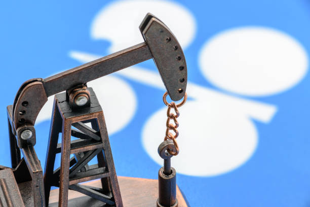 Petroleum, petrodollar and crude oil concept : Oil pump jack and flag of OPEC or Organization of Oil Exporting Countries, depicts the investment in the development or production of global oil industry stock photo