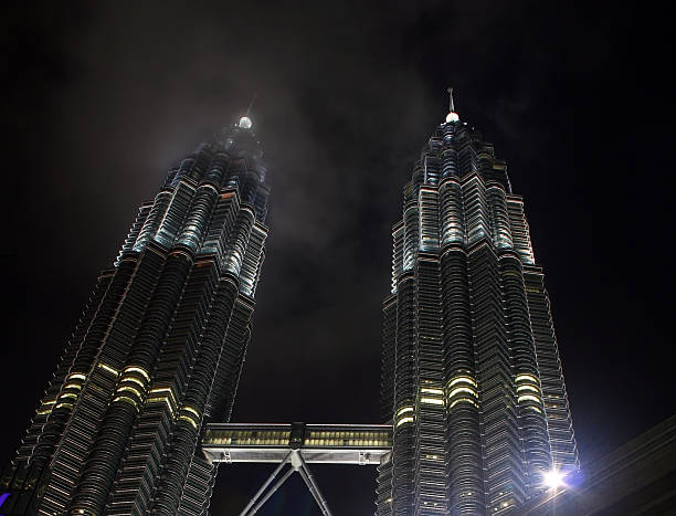 Petronas Twin Towers At Night Petronas Twins Towers in Kuala Lumpur, Malaysia - lighting up the sky on a cloudy night. central market kuala lumpur stock pictures, royalty-free photos & images
