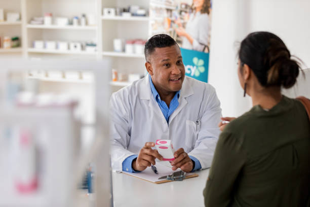Pharmacist explains side effects of generic drug to unrecognizable customer The mature adult pharmacist takes time to explain the side effects of a generic drug to an unrecognizable customer. generic drug stock pictures, royalty-free photos & images