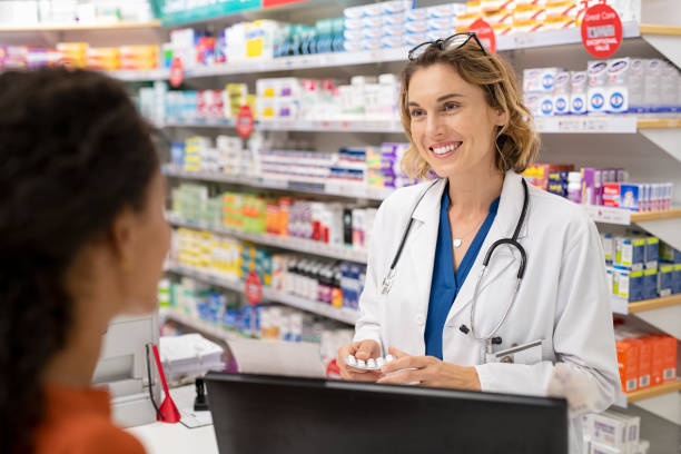 Pharmacist giving medicine to customer Pharmacist giving medicine to customer in modern pharmacy. Rear view of young woman buying analgesic at pharmacy. Happy doctor giving strip of tablet to customer. Pharmaceutical Representatives stock pictures, royalty-free photos & images