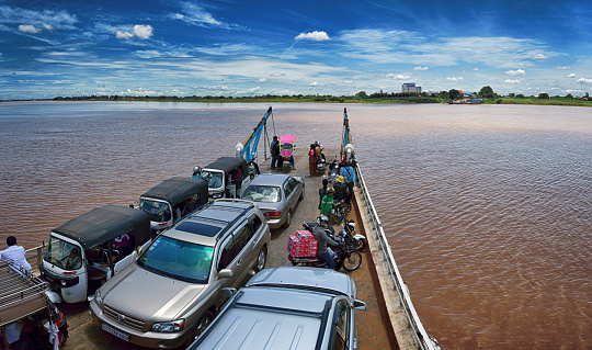 Phnom Penh, Cambodia -cars, motorbikes and people on a ferry crossing the Mekong river