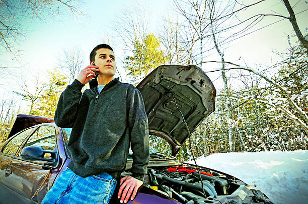 Phoning for Roadside Assistance (Xpro) Youth driver whose car is broken down on winter road seeks help via cell phone. Cross-processed for effect. mike cherim stock pictures, royalty-free photos & images