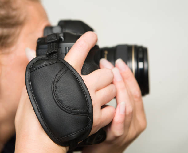A photo camera with a wrist belt in beautiful female hands. stock photo