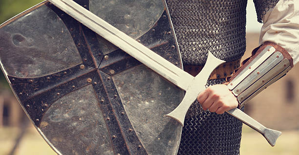 A photo of a knight in armor holding a sword and shield stock photo