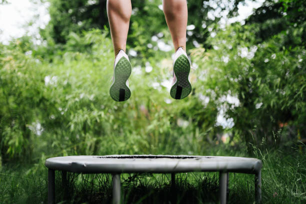 foto di una donna sportiva che salta su un trampolino - tappeto elastico foto e immagini stock