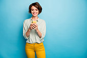 Photo of attractive lady holding telephone hands reading new blog post positive, comments popular blogger wear casual green shirt yellow trousers isolated blue color background