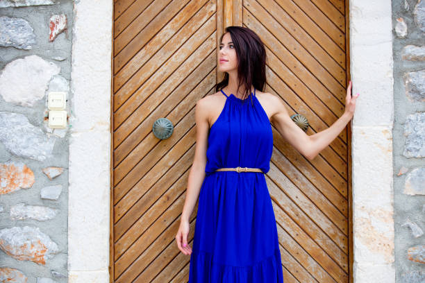 photo of beautiful young woman standing near the wooden old door in Greece stock photo