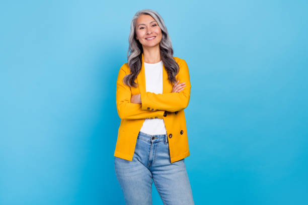 Photo of charming confident mature woman wear yellow jacket smiling arms crossed isolated blue color background stock photo