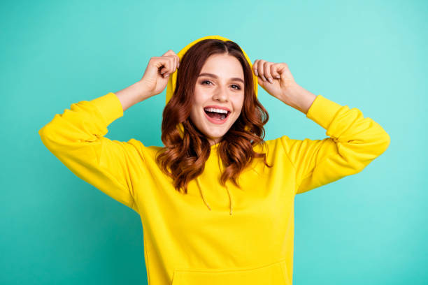 Photo of cheerful cute nice charming pretty sweet putting her hood on smiling toothily beaming isolated over teal vivid color background Photo of cheerful cute nice charming pretty sweet putting her hood on smiling, toothily beaming isolated over teal vivid color background hooded shirt stock pictures, royalty-free photos & images