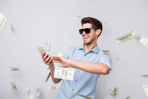 Photo of cheerful excited ecstatic overjoyed man throwing money away showing his wealthiness wearing denim isolated over grey color background Photo of cheerful excited ecstatic overjoyed man throwing money away, showing his wealthiness wearing denim isolated over grey color background money rain stock pictures, royalty-free photos & images