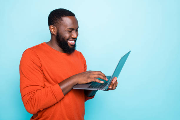 foto van vrolijke mens die door zijn laptop glimlacht die toothily het maken van nieuwe video glimlacht die op zijn sociale media geïsoleerde levendige blauwe kleurenachtergrond kan worden bekeken - gekleurde achtergrond stockfoto's en -beelden