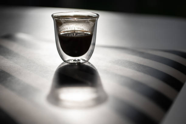 Photo of cup with black coffee and shadow on black and white background stock photo