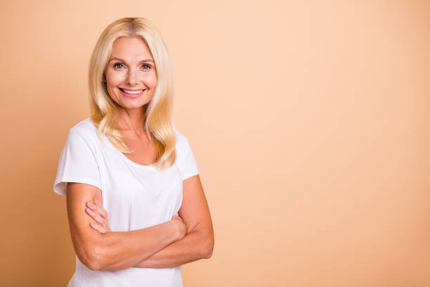 Photo of middle age lady arms crossed pretty neat appearance boss wear white casual t-shirt isolated pastel beige background Photo of middle age lady arms crossed pretty neat appearance boss, wear white casual t-shirt isolated pastel beige background mature women beauty beautiful fashion model stock pictures, royalty-free photos & images