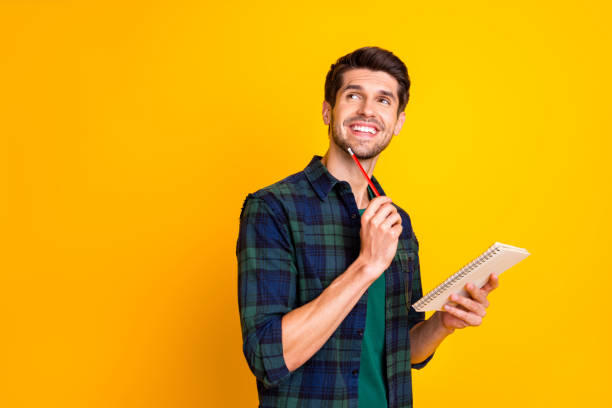 foto av trevlig kille med arrangör i händerna gör anteckningar skapa startup idé slitage casual rutig skjorta isolerad gul färg bakgrund - man writing bildbanksfoton och bilder