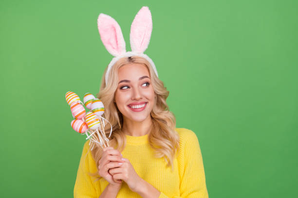 Photo of nice young blond lady hold eggs look promo wear ears yellow pullover isolated on green color background stock photo