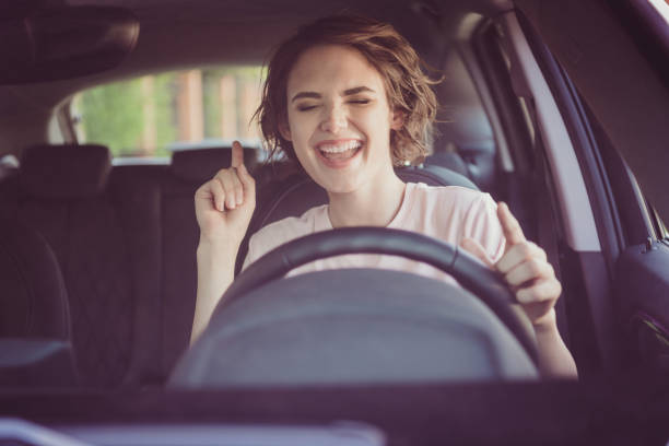 Photo of positive cheerful girl ride drive car town route wait traffic jam listen music sound try dance feel excited Photo of positive cheerful girl ride drive car town route wait traffic jam listen, music sound try dance feel excited singing stock pictures, royalty-free photos & images