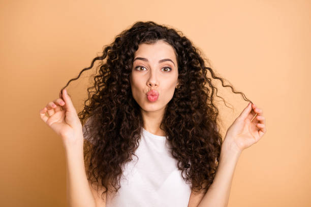 Photo of pretty funny lady showing perfect wavy perming curls in fingers sending air kisses wear white casual clothes isolated beige pastel color background Photo of pretty funny lady showing perfect wavy perming curls in fingers, sending air kisses wear white casual clothes isolated beige pastel color background curly hair stock pictures, royalty-free photos & images