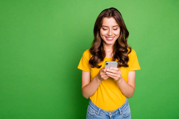 Photo of pretty wavy lady holding telephone hands reading website blog new interesting post wear casual yellow t-shirt jeans isolated bright green color background Photo of pretty wavy lady holding telephone hands reading website, blog new interesting post wear casual yellow t-shirt jeans isolated bright green color background smart phone green background stock pictures, royalty-free photos & images