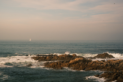 photo of sea with rocks and boat in the background