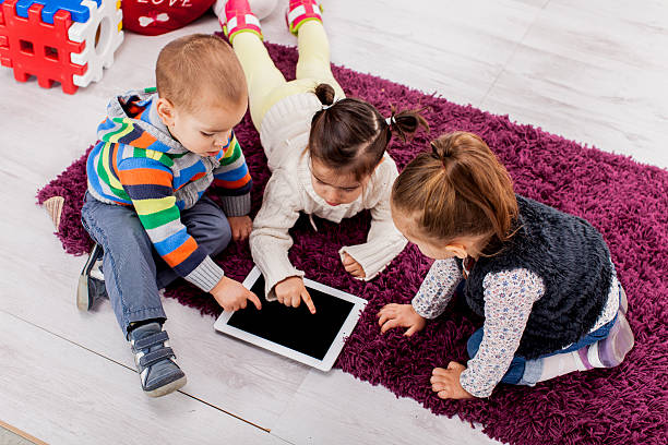 Photo of three toddlers using a tablet computer stock photo