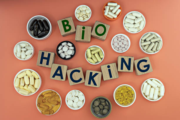 photo on biohacking theme. wooden cubes with the inscription "biohacking", and biologically active supplements, on coral background stock photo