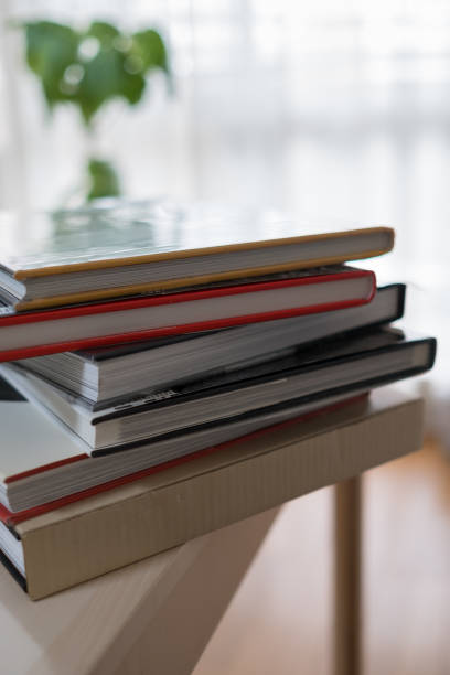 Photobooks piled up on the desk , interior , By the window stock photo