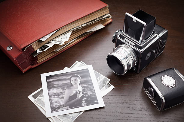 Photograph of retro styled cameras and photos Red photo album with old photos and middle format camera on wooden table; black and white photo of young woman on foreground collection photos stock pictures, royalty-free photos & images