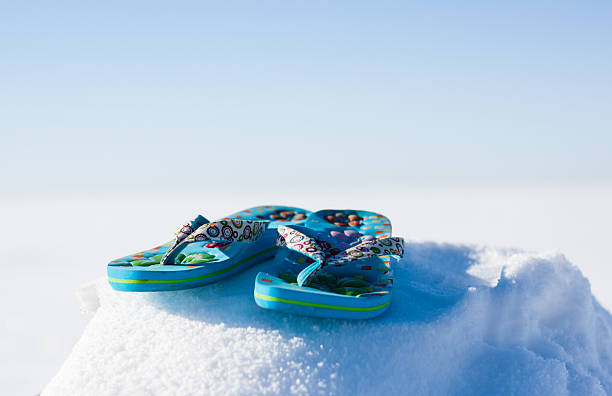 Photograph of summer sandals sitting atop a snowbank stock photo