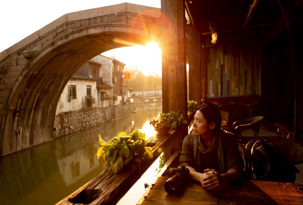 Photographer in Chinese Village Photographer reflecting upon journey in Nanxun ancient town near Wuzhen, China. wuzhen stock pictures, royalty-free photos & images