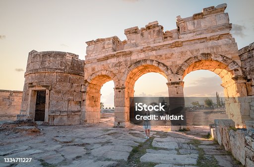istock Photographer tourist is smiling  in front of the Frontinus Gate in ancient ruins in Hierapolis , Pamukkale 1334711227