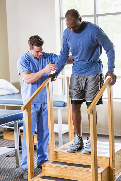 Physical therapist helping patient on stairs Physical therapist helping patient on exercise staircase. orthopedics stock pictures, royalty-free photos & images