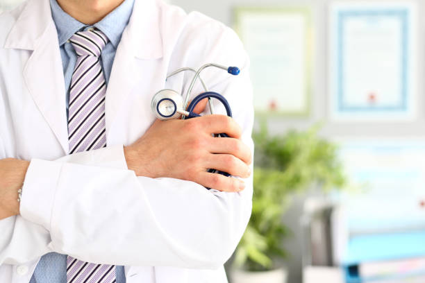 Physician holding stethoscope Close up of crossed male hands with medical instrument for listening to action of heart or breathing. Medicine and health care concept.Blurred background general view stock pictures, royalty-free photos & images