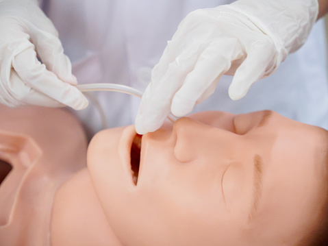 Close-up detail of a physician inserting a nasogastric tube into a training model. Healthcare and education concept.